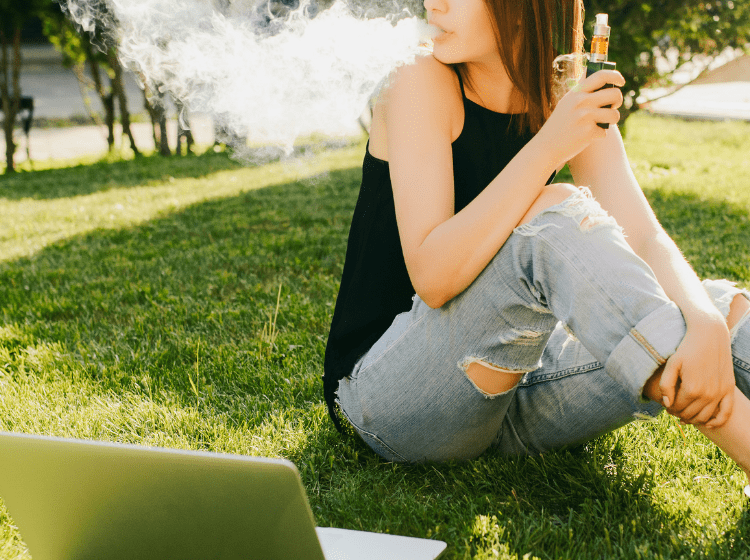 woman vaping cannabis outside at college while studying