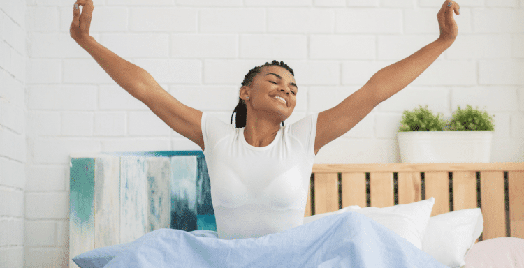 young black woman in white shirt waking up in the morning out of bed